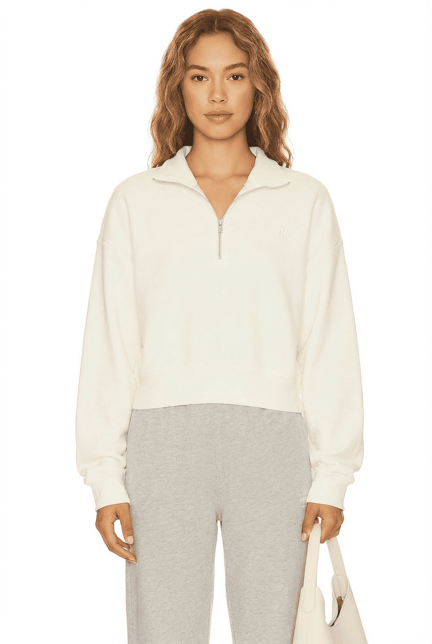 Model wearing off-white half-zip cropped sweatshirt, front view styled with heather grey sweatpants and a white tote bag
