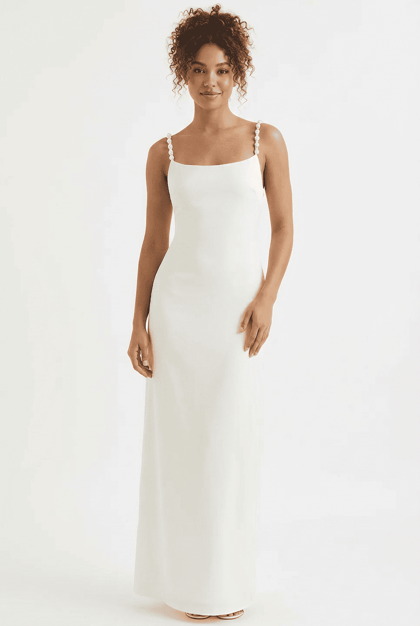 Model wearing white satin maxi dress, front view styled with nude strappy heeled sandals, showcasing the pearl-embellished straps and square neckline