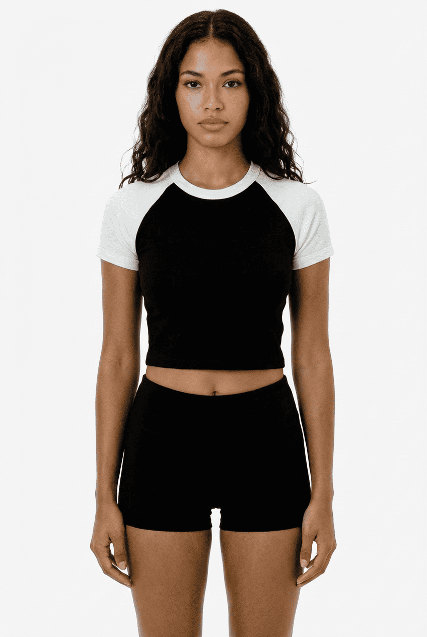 ：Model wearing black and white raglan sleeve cropped tee, front view with black high-waisted shorts