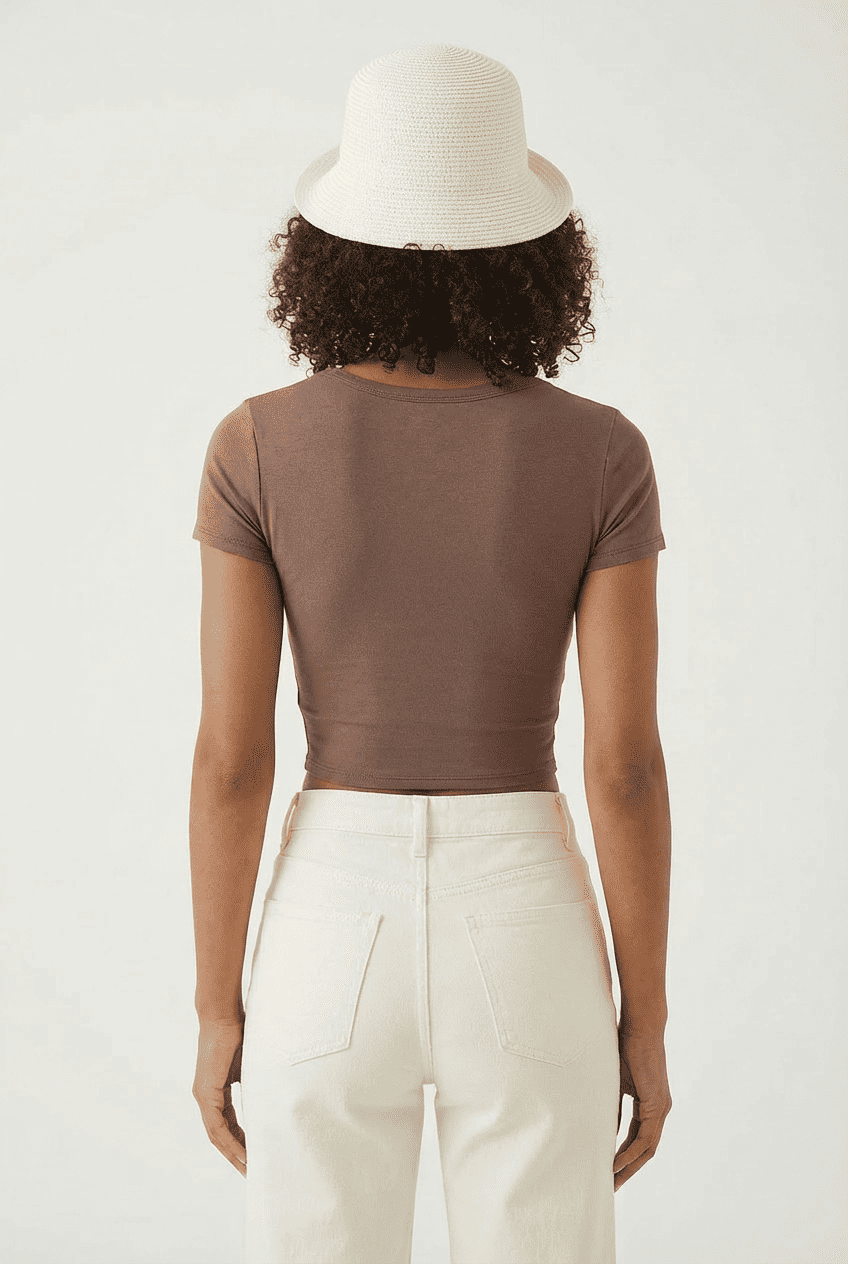 Model wearing mocha brown cropped scoop-neck tee, back view styled with off-white high-waisted jeans and a white woven bucket hat