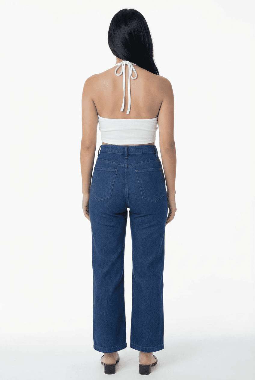 Model wearing white halter-neck cropped top with tie-back detail, back view with dark blue high-waisted wide-leg jeans