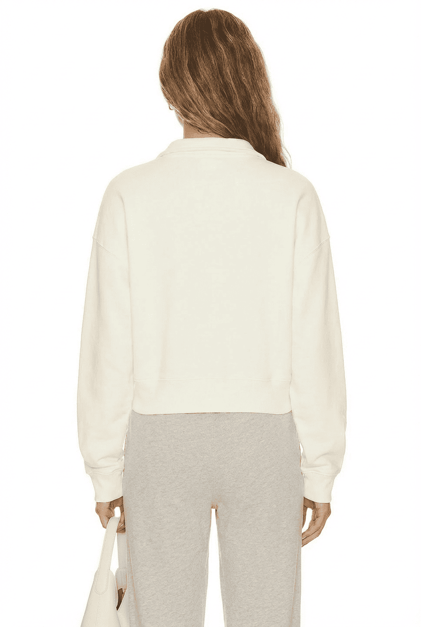 Model wearing off-white half-zip cropped sweatshirt, back view showing relaxed fit and cropped hem, paired with heather grey sweatpants