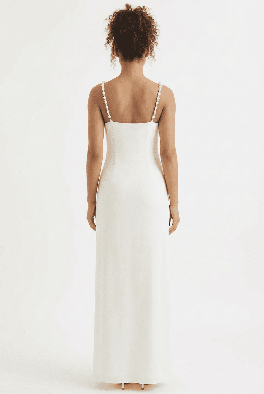 Model wearing white satin maxi dress, back view featuring pearl-embellished spaghetti straps and an open-back design