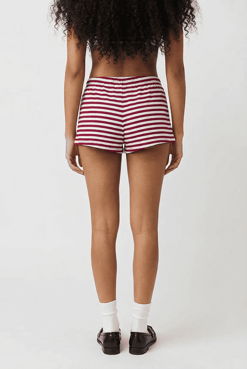 Model wearing red and white striped low-rise lounge shorts, back view styled with white crew socks and black loafers
