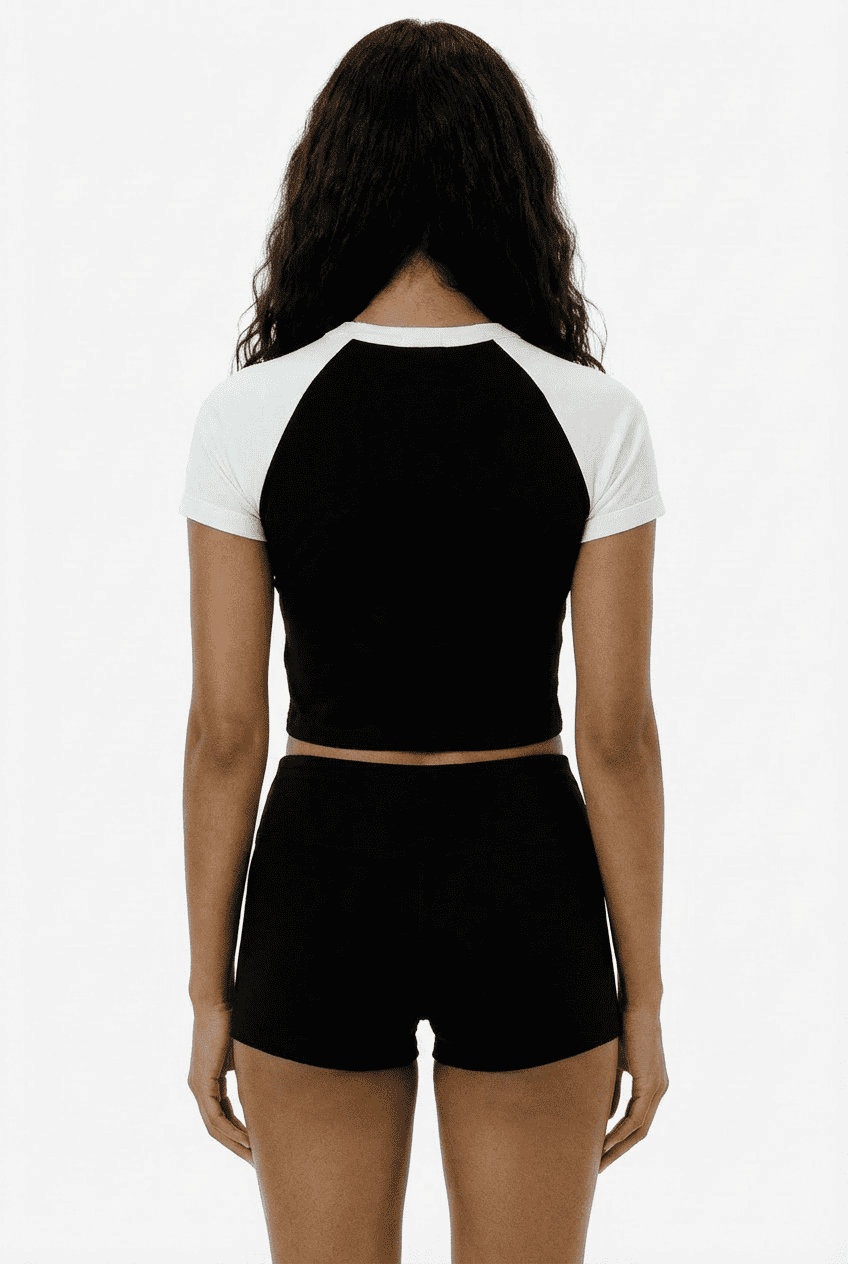 Model wearing black and white raglan sleeve cropped tee, back view with black high-waisted shorts