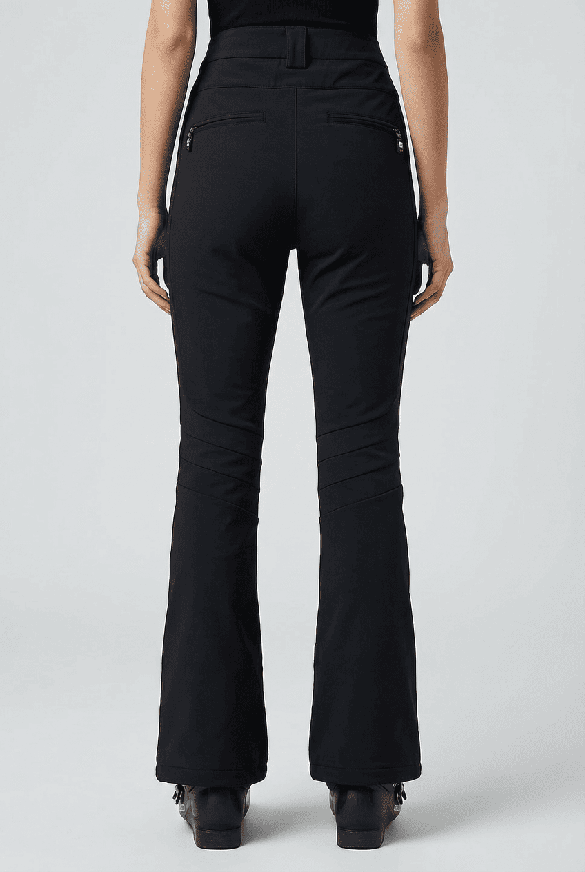 Model wearing black high-waisted flared ski pants, back view showing zip back pockets, knee seam detailing, and bootcut hems